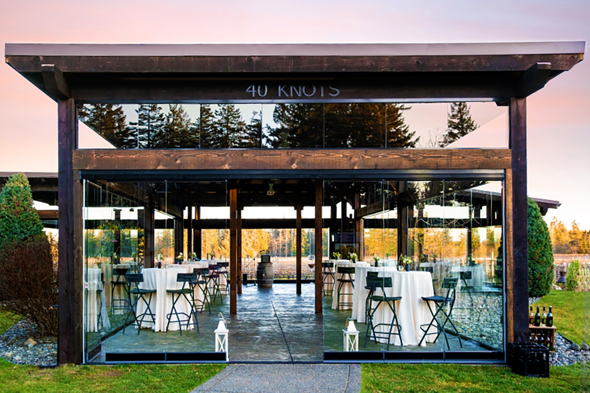Image of stunning vineyard terrace with glass walls and wrought iron tables and chairs.