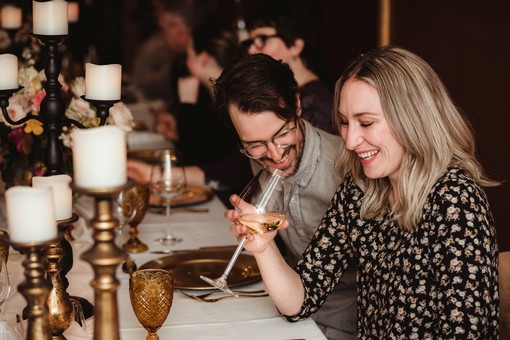 image of couple at crowded table, laughing and drinking wine.