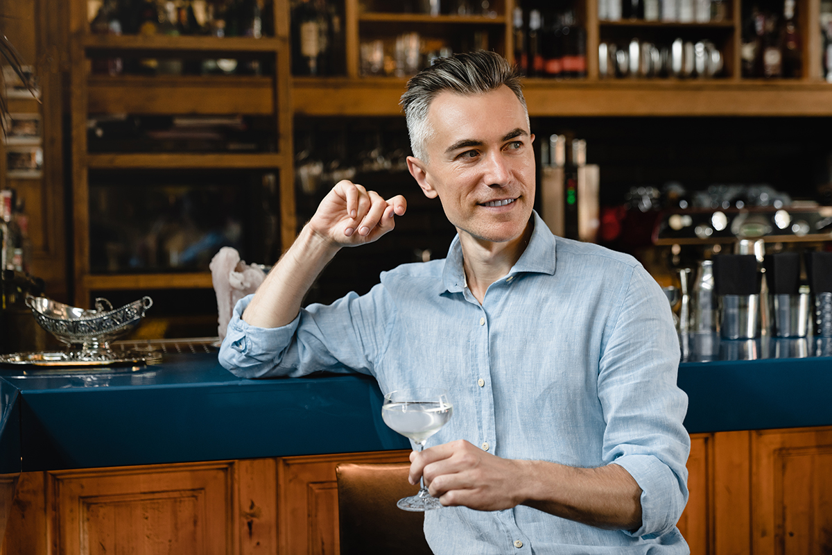 Image of business man drinking sparkling wine while standing at the bar.