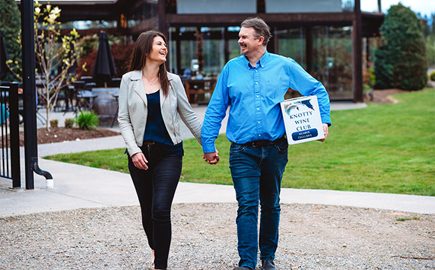 Couple walking out of 40 Knots tasting room with a case of wine