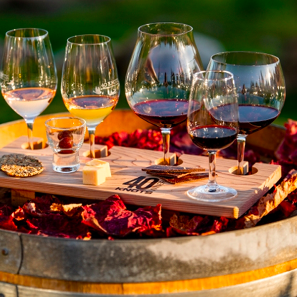Image of  wine glasses filled with a variety of wines, sitting on an oak barrel.