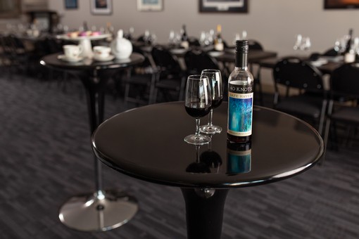 image of standup cocktail table with two wine glasses and bottle of red wine.