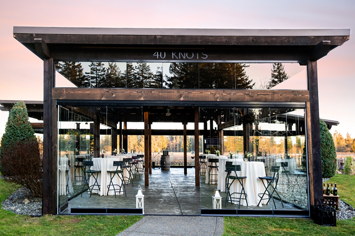 Image of stunning vineyard terrace with glass walls and wrought iron tables and chairs.