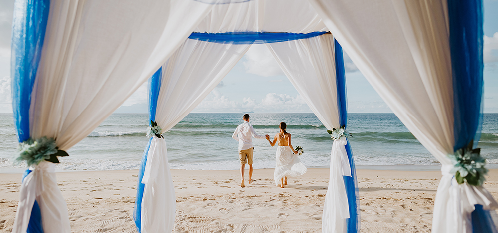 Image of bride and groom walking on beach.