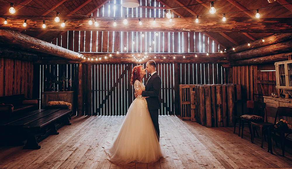 Image of bride and groom dancing in decorated barn.