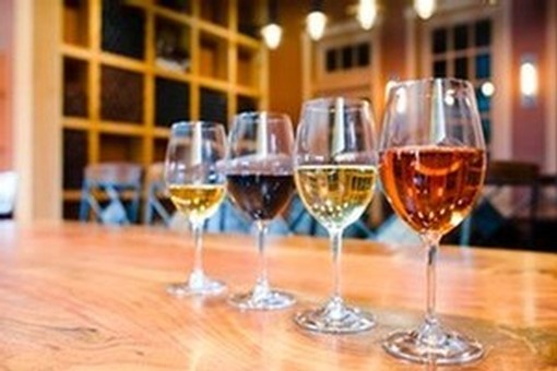 image of four wine glasses on a wooden bar with different varieties of wine.